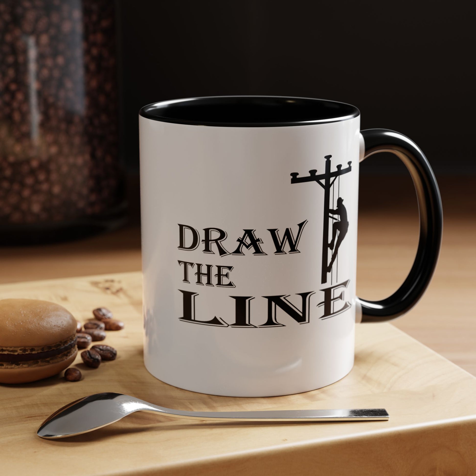 Mug with 'Draw the Line' design on a wooden surface with coffee beans and a spoon.