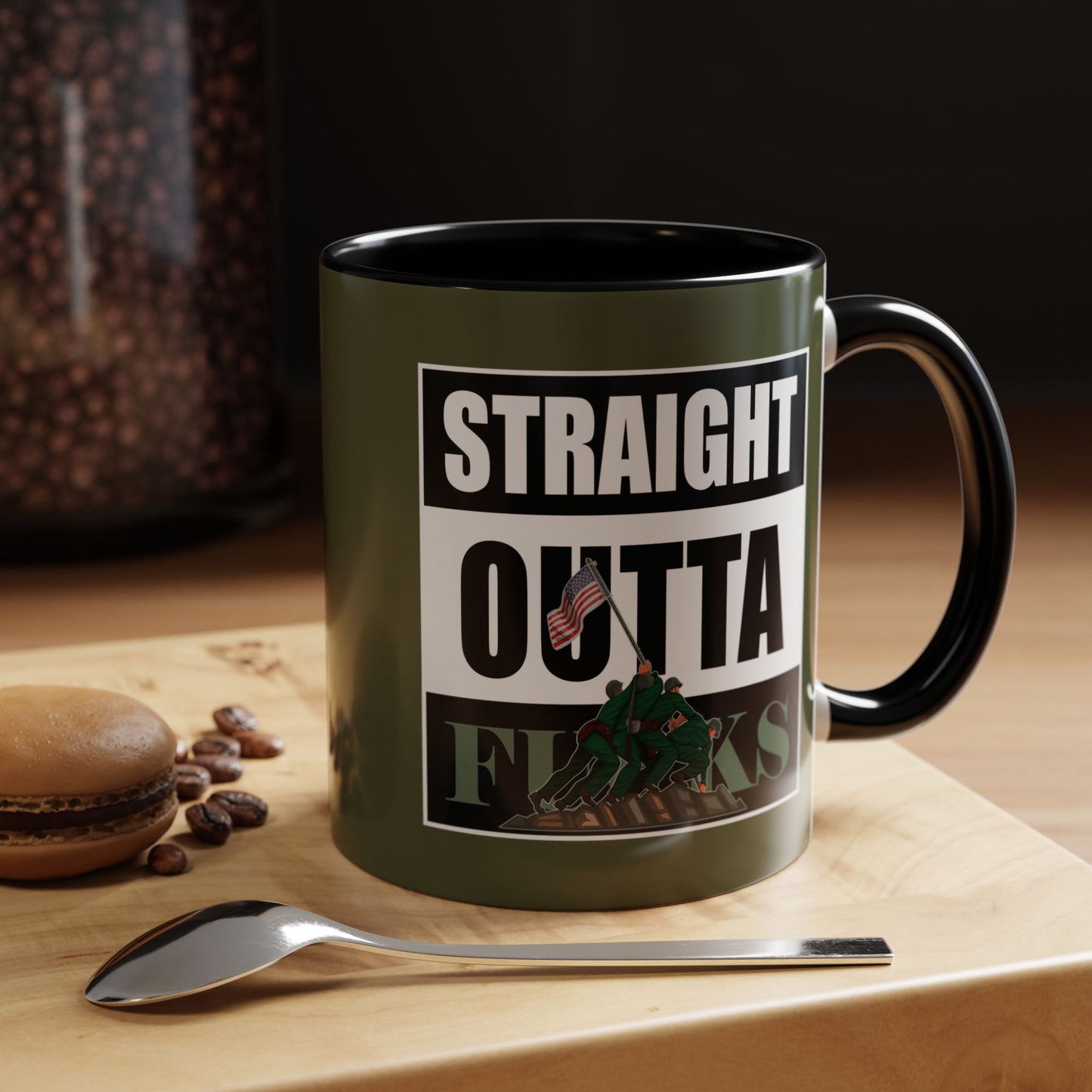 Mug with 'Straight Outta' design on a wooden surface with coffee beans and a macaron.