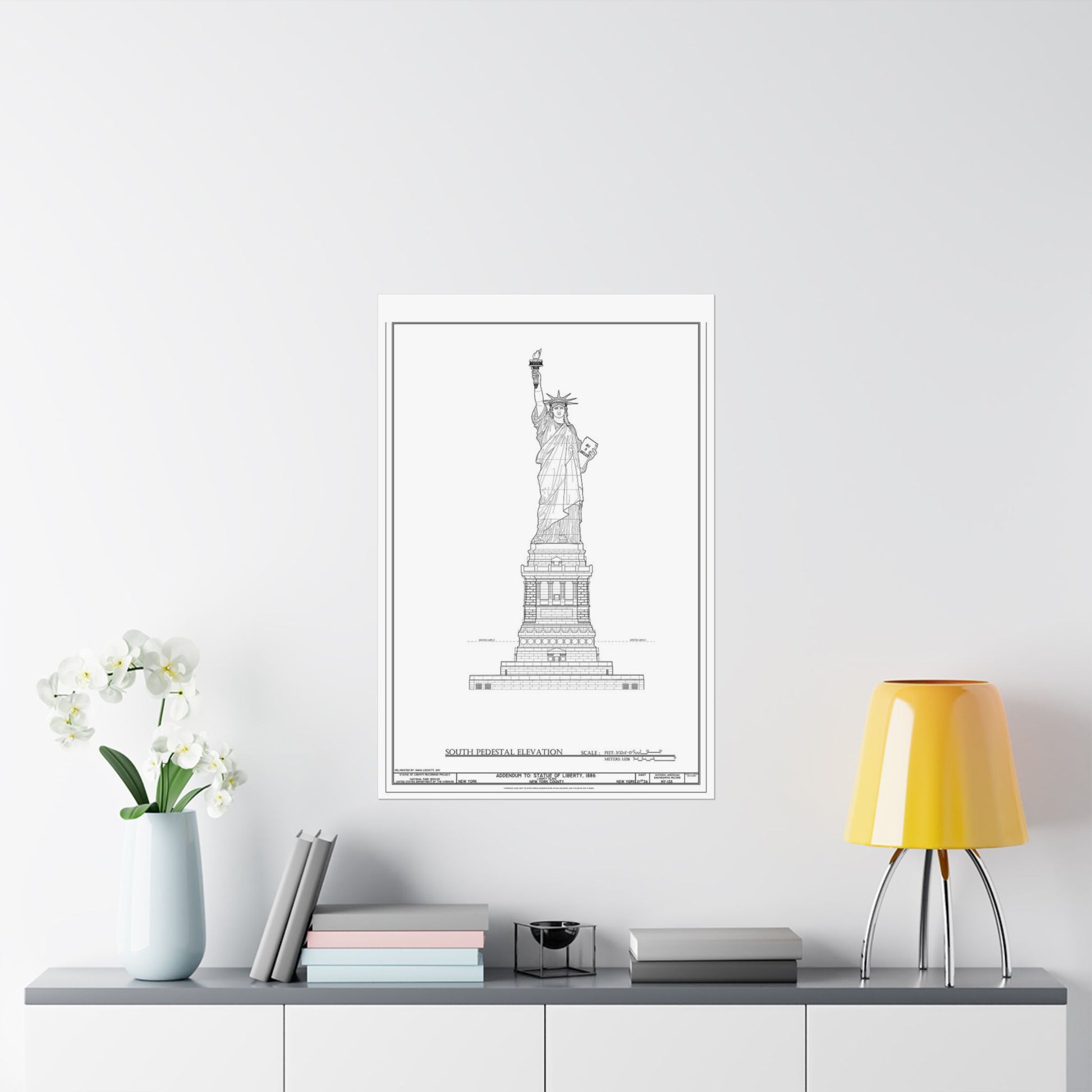 Framed black and white print of the Statue of Liberty on a wall above a desk with decor items.