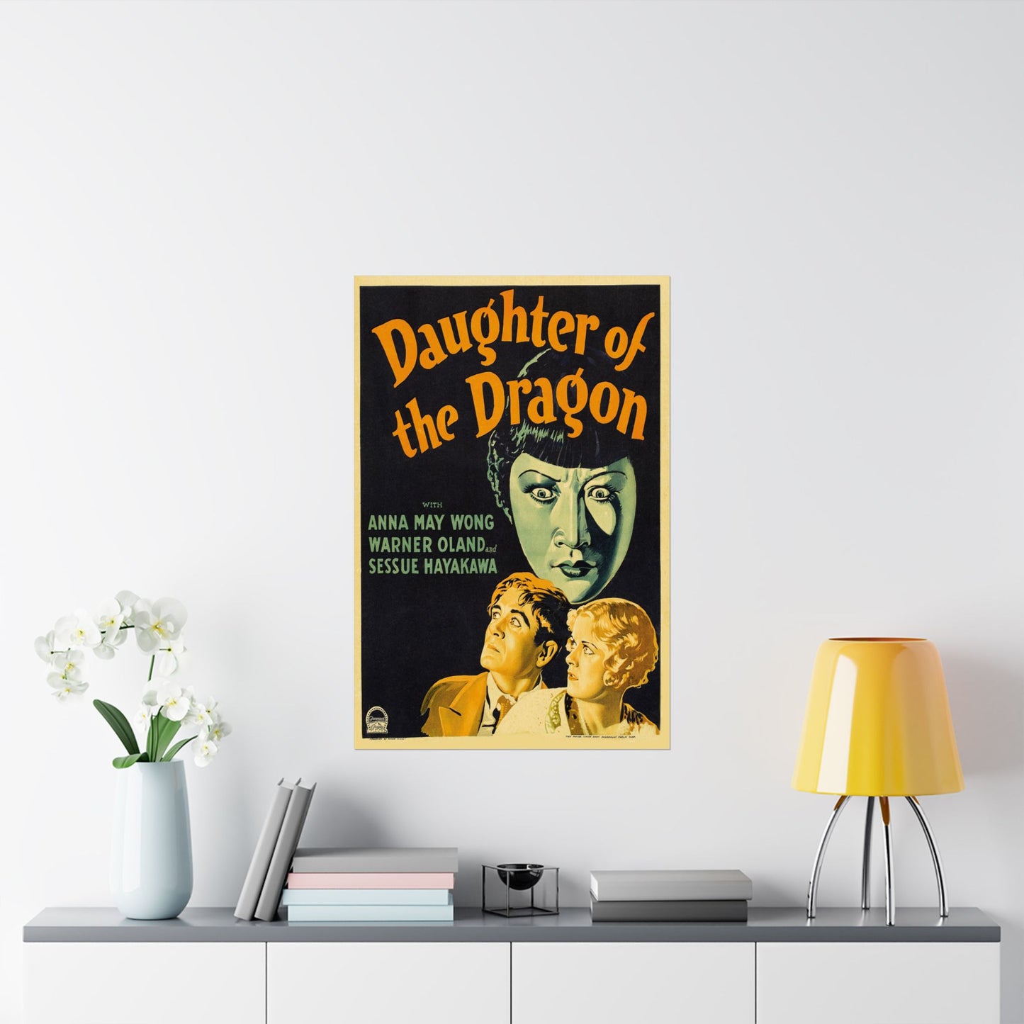 Vintage movie poster for 'Daughter of the Dragon' on a wall above a shelf with decor items.
