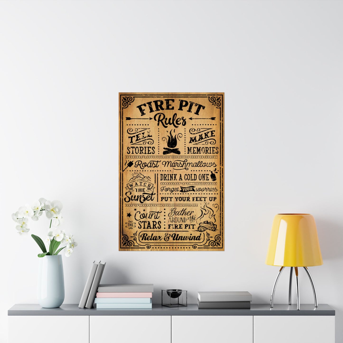 Decorative poster with text on a wall above a table with a lamp and books.
