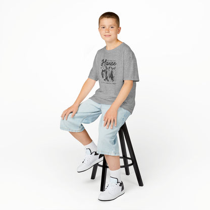 Young boy sitting on a stool wearing a gray t-shirt, light blue jeans, and white sneakers on a white background
