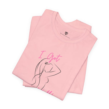 Folded pink t-shirt with 'I Got' text and a line drawing on a white background