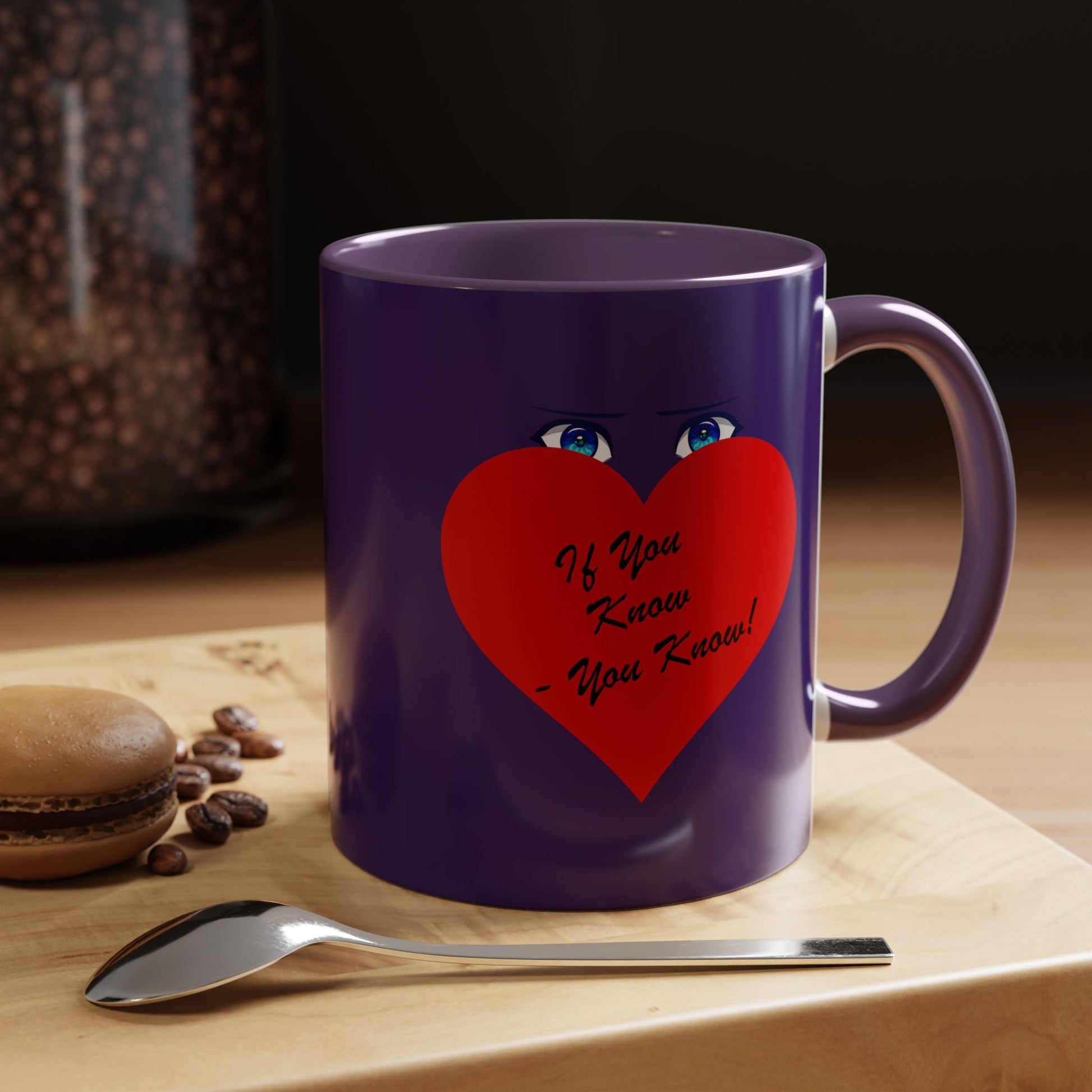 Purple mug with a red heart and text on a wooden surface with coffee beans and a spoon.