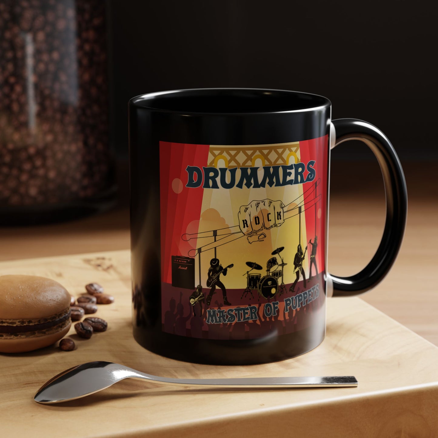 Black mug with a colorful design featuring 'DRUMMERS ROCK' on a wooden surface with coffee beans and a spoon.
