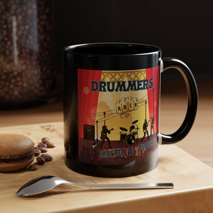 Black mug with a colorful design featuring 'DRUMMERS ROCK' on a wooden surface with coffee beans and a spoon.