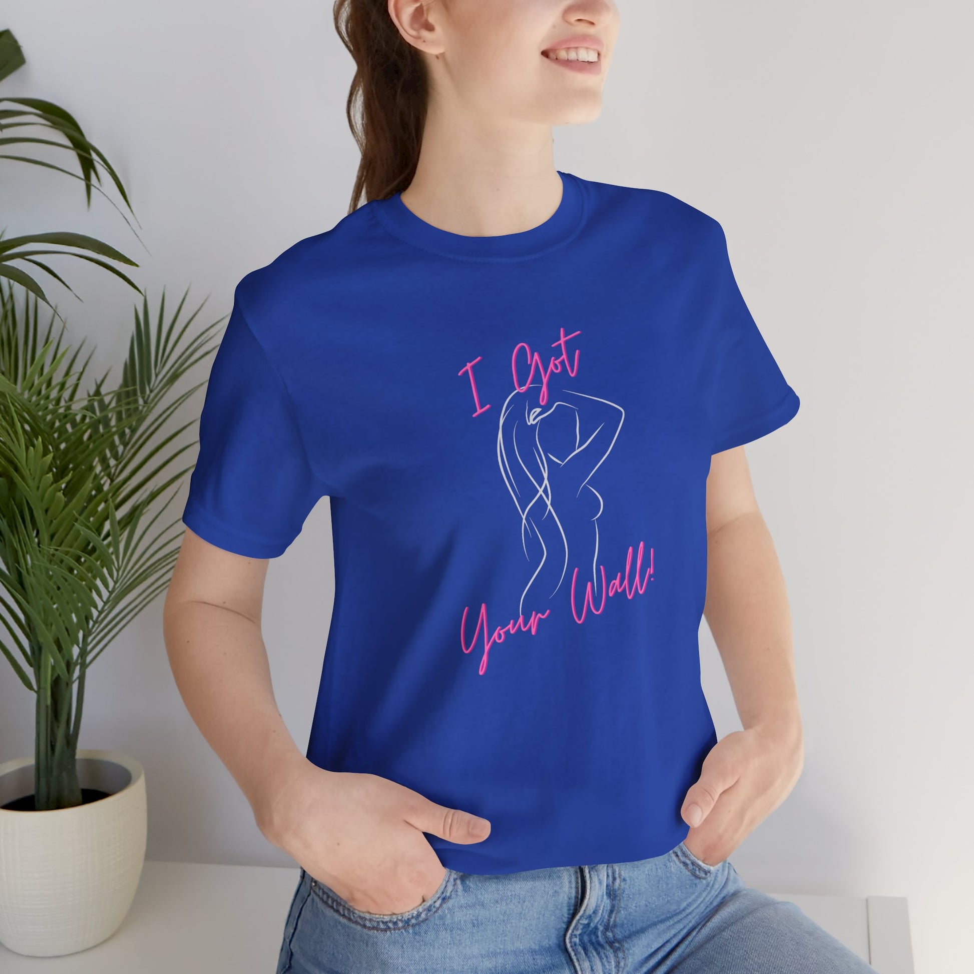 Person wearing a blue t-shirt with pink text and design, standing indoors.