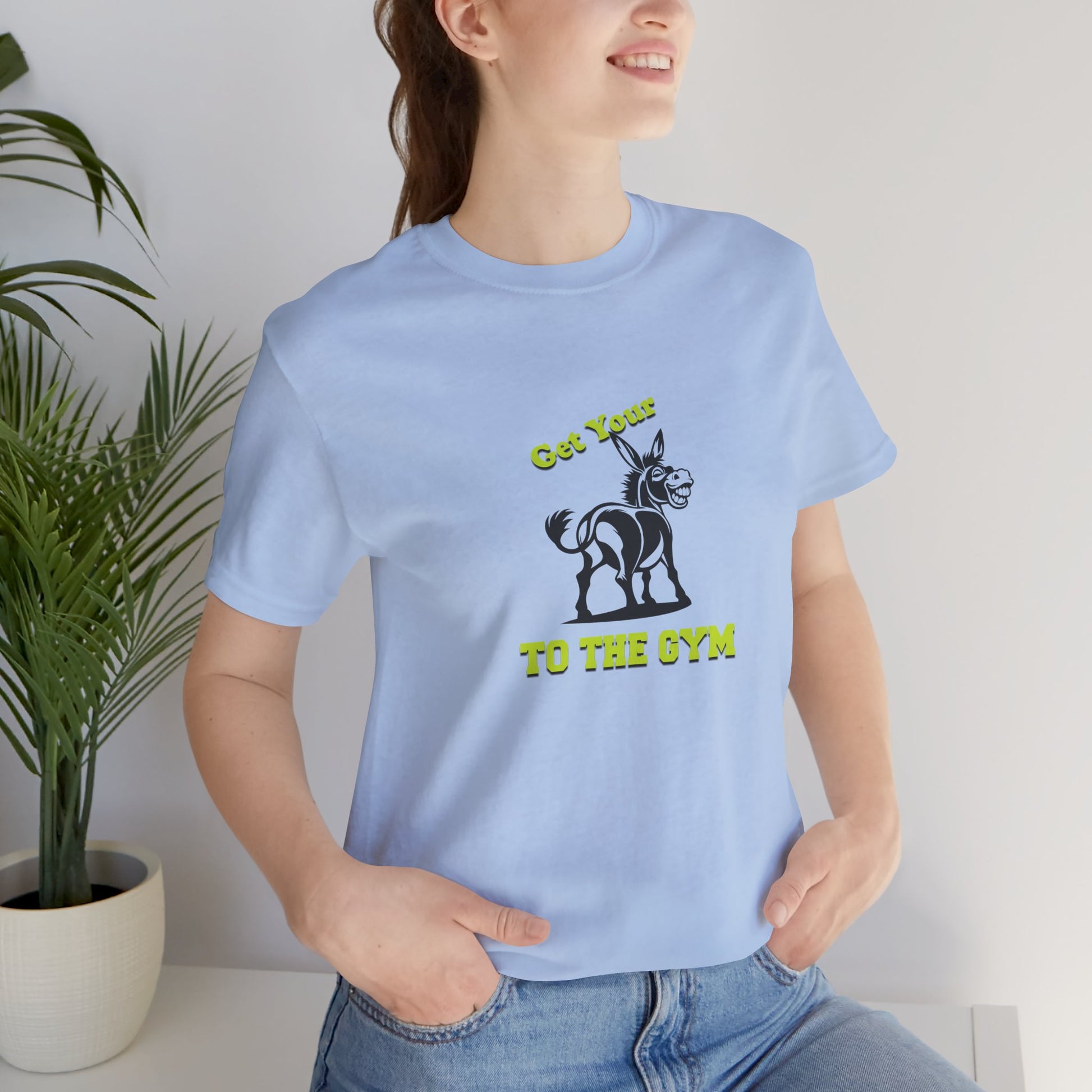 Person wearing a light blue t-shirt with a donkey graphic and text, standing indoors.