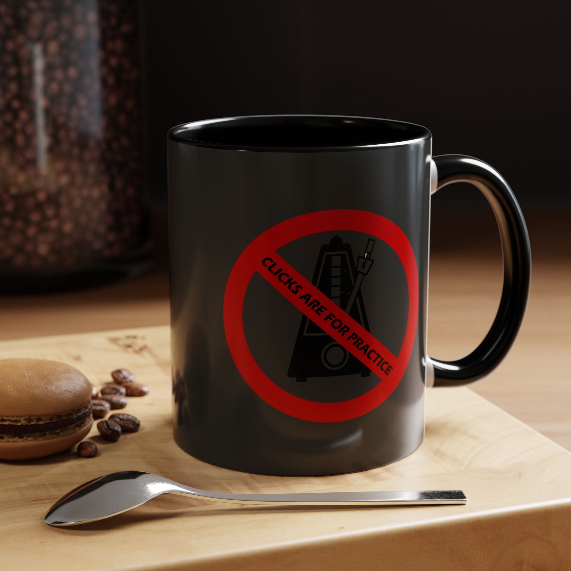 Black mug with a red prohibition sign and text on a wooden surface with coffee beans and a spoon.