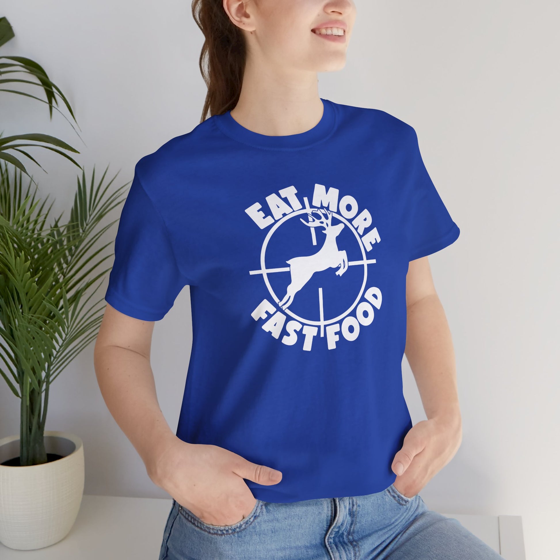 Person wearing a blue t-shirt with a graphic design and text, standing indoors.