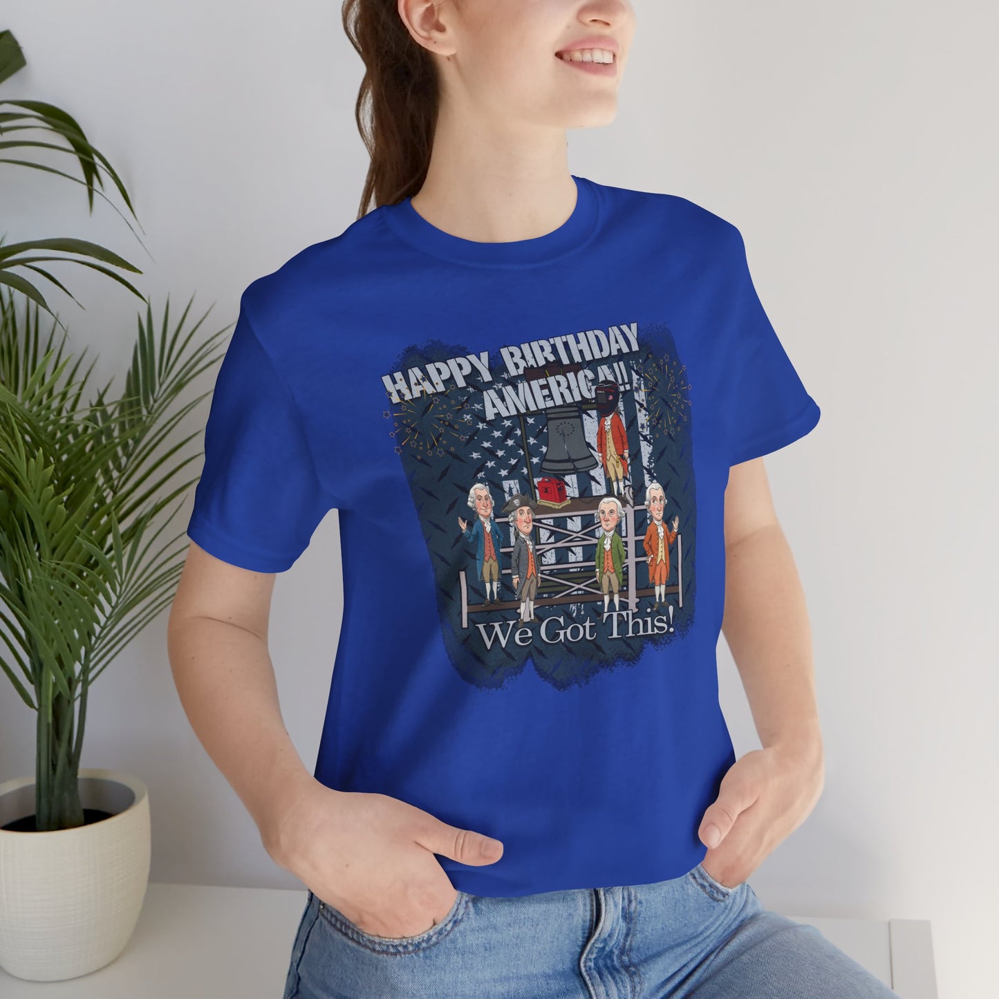 Person wearing a blue t-shirt with a graphic design and text, standing indoors.