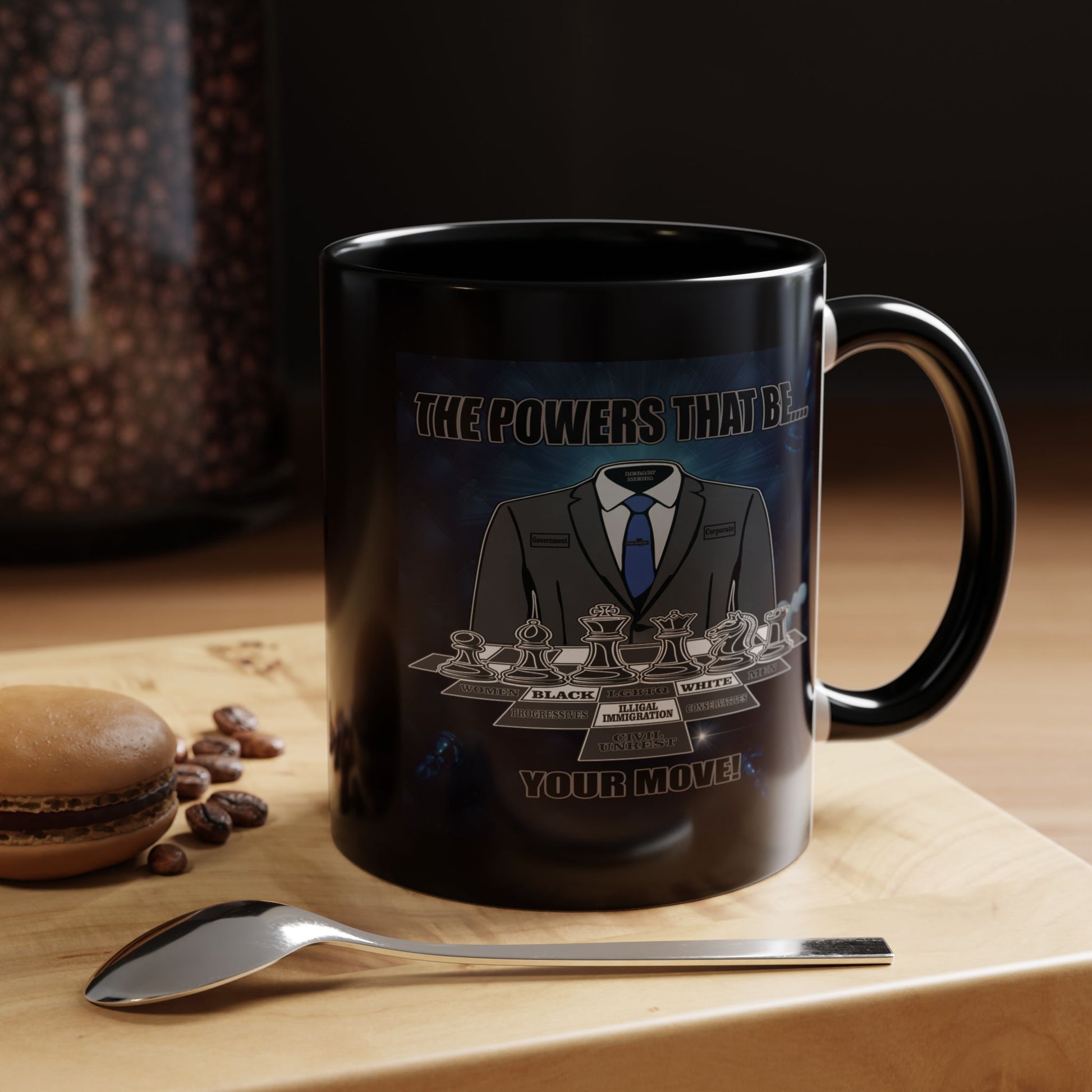 A black ceramic coffee mug with a custom chess-themed graphic, displayed on a wooden surface next to a spoon and a macaron with coffee beans. The mug features a chess knight in a suit and the text.