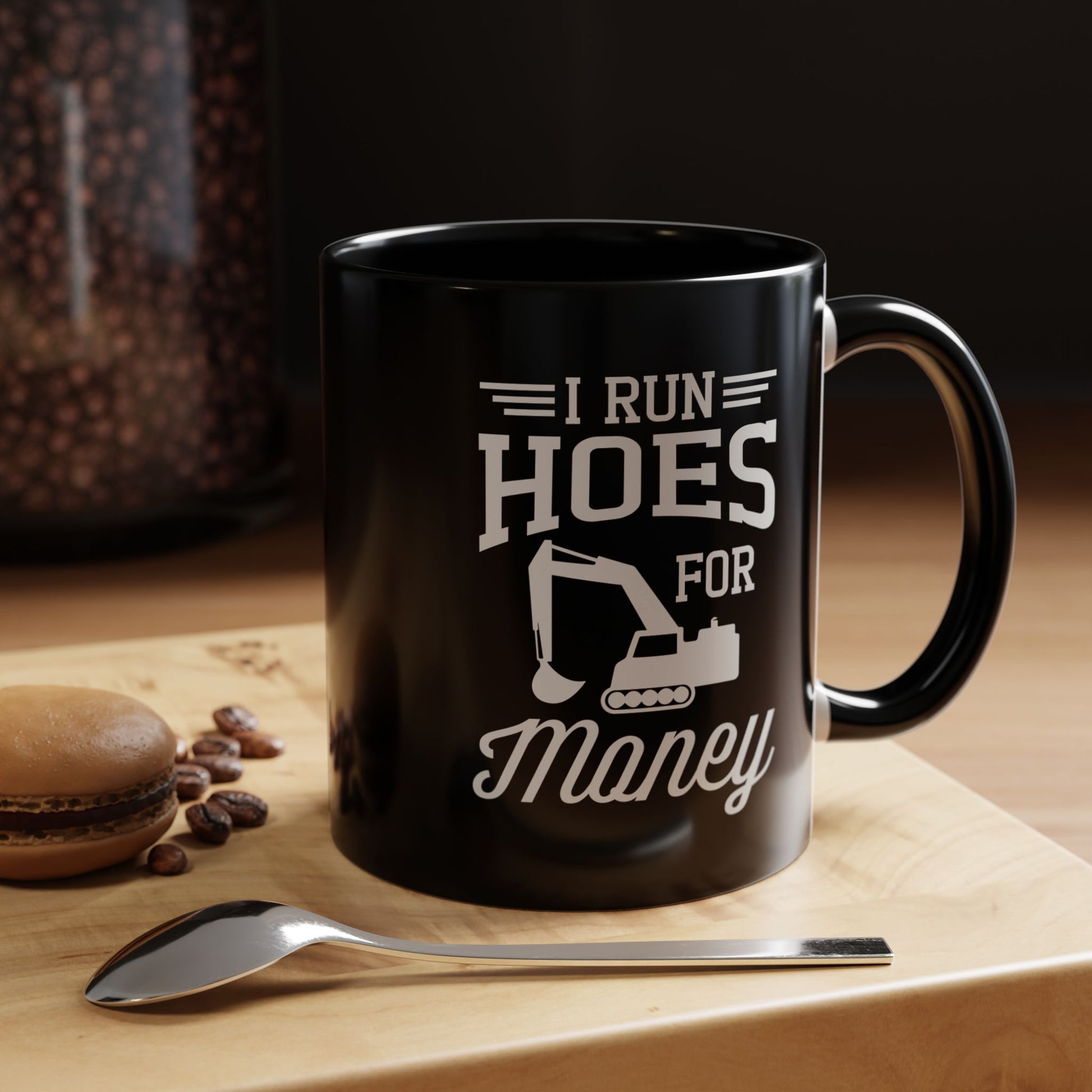 Black mug with offensive text on a wooden surface with coffee beans and a spoon.