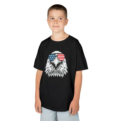 Child wearing a black t-shirt with an eagle design and American flag sunglasses on a white background