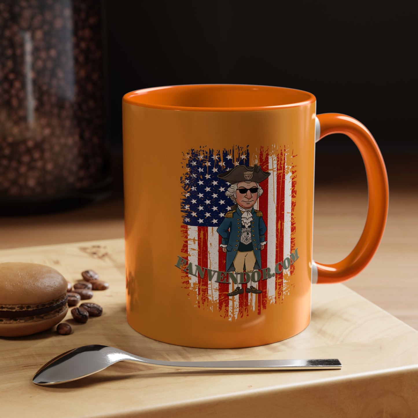 Orange mug with a graphic of a historical figure and American flag, placed on a wooden surface with coffee beans and a spoon.