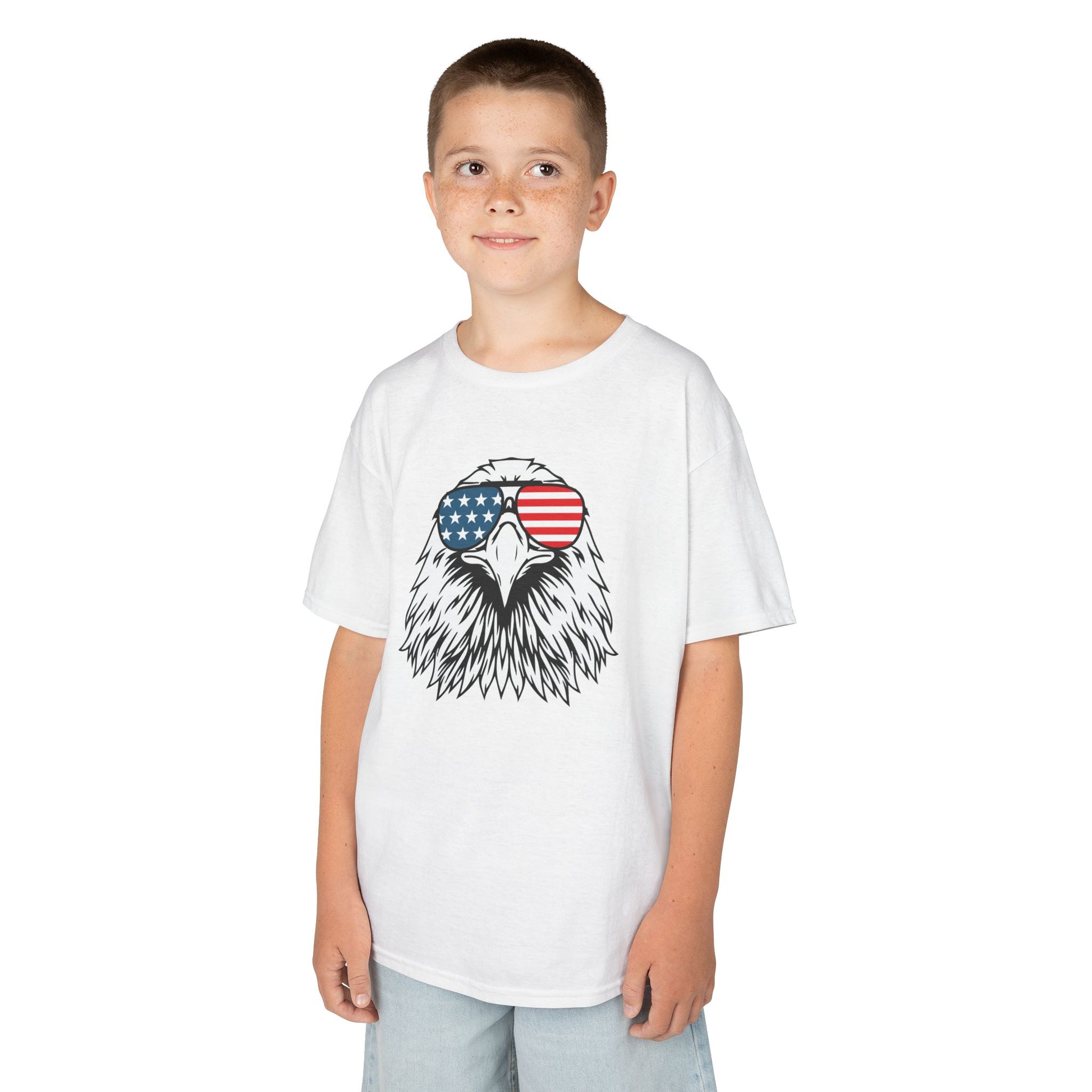 Child wearing a white t-shirt with an eagle design and American flag sunglasses on a white background