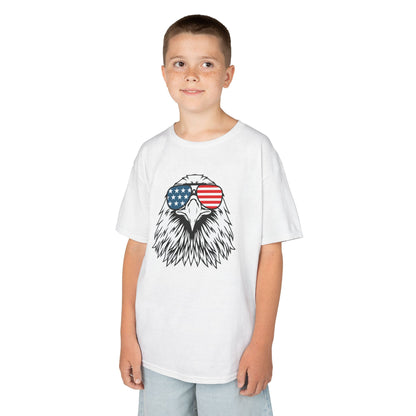 Child wearing a white t-shirt with an eagle design and American flag sunglasses on a white background