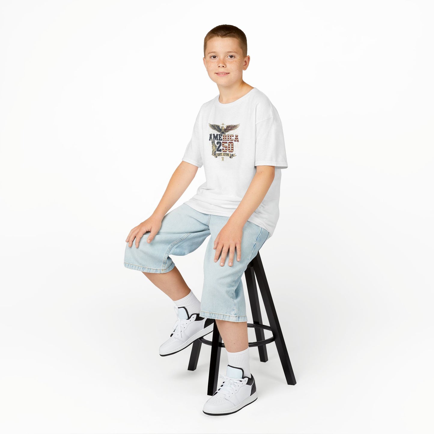 Child sitting on a stool wearing a white t-shirt with colorful text and light blue jeans on a white background