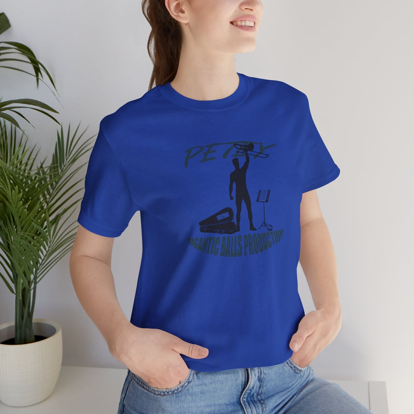 Person wearing a blue t-shirt with a graphic design in a room with a plant.