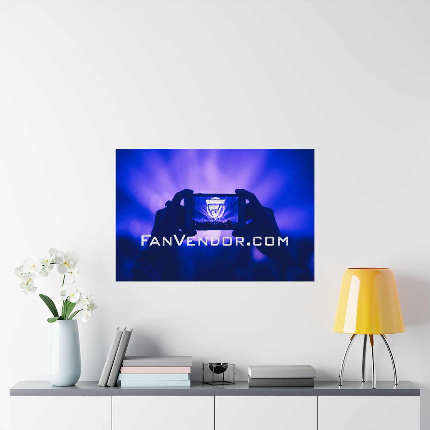 Wall-mounted poster displaying 'FanVendor.com' on a white wall with decor items below.