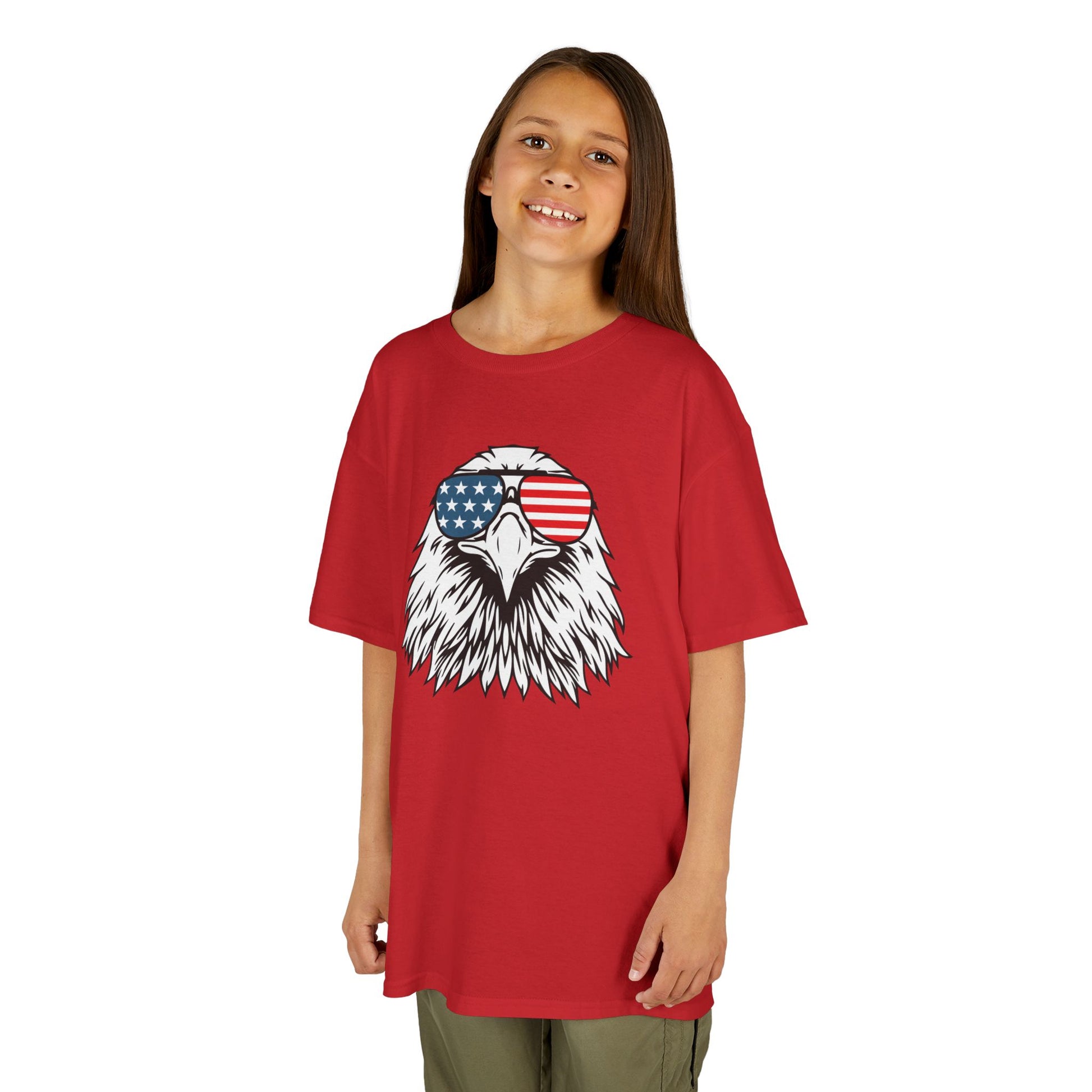 Child wearing a red t-shirt with an eagle graphic and American flag sunglasses on a white background