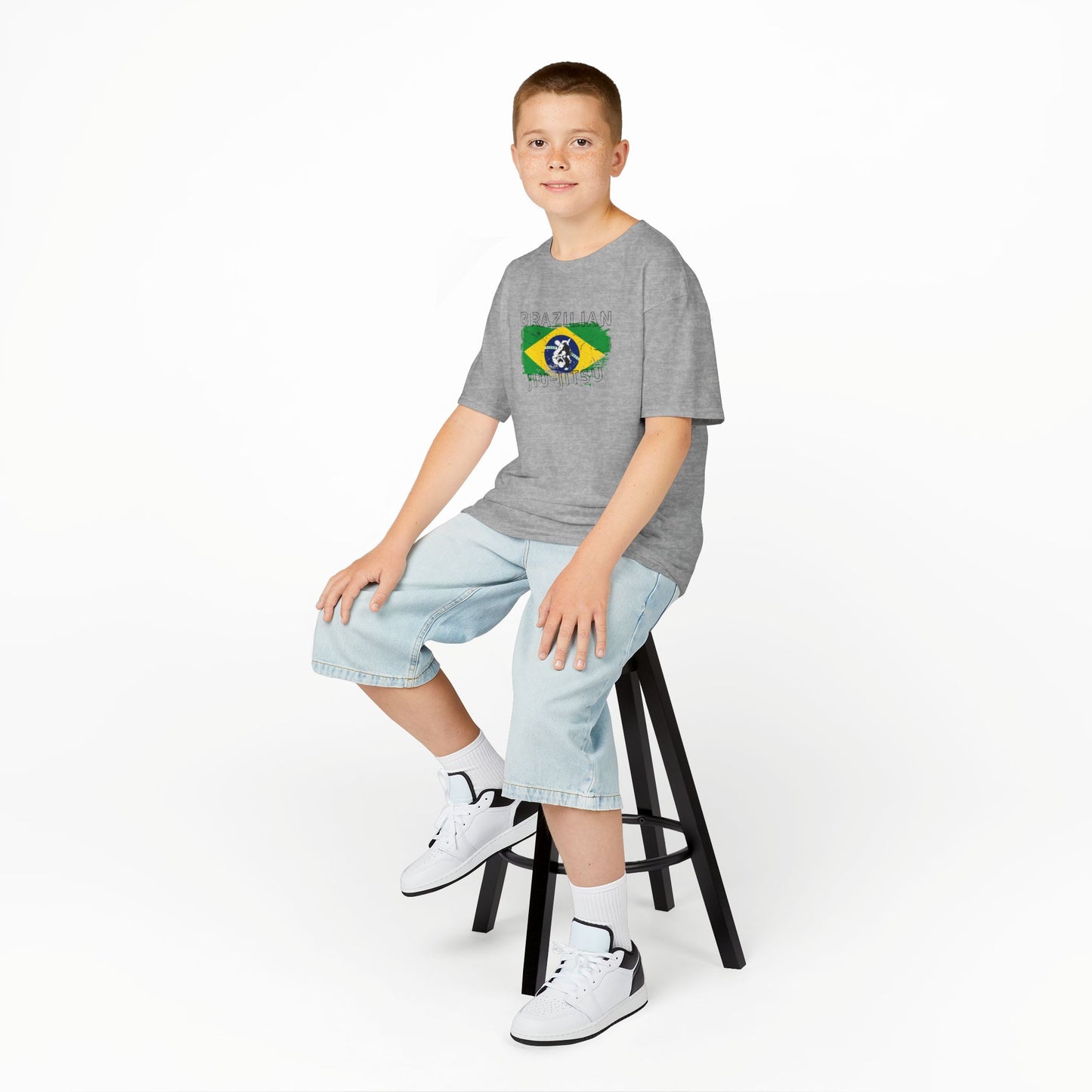 Child sitting on a stool wearing a gray t-shirt on a white background