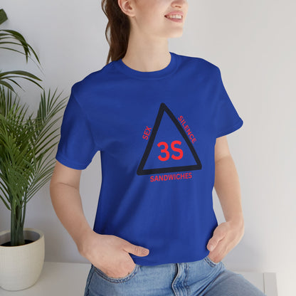 Person wearing a blue t-shirt with a graphic design, standing indoors with a plant in the background.