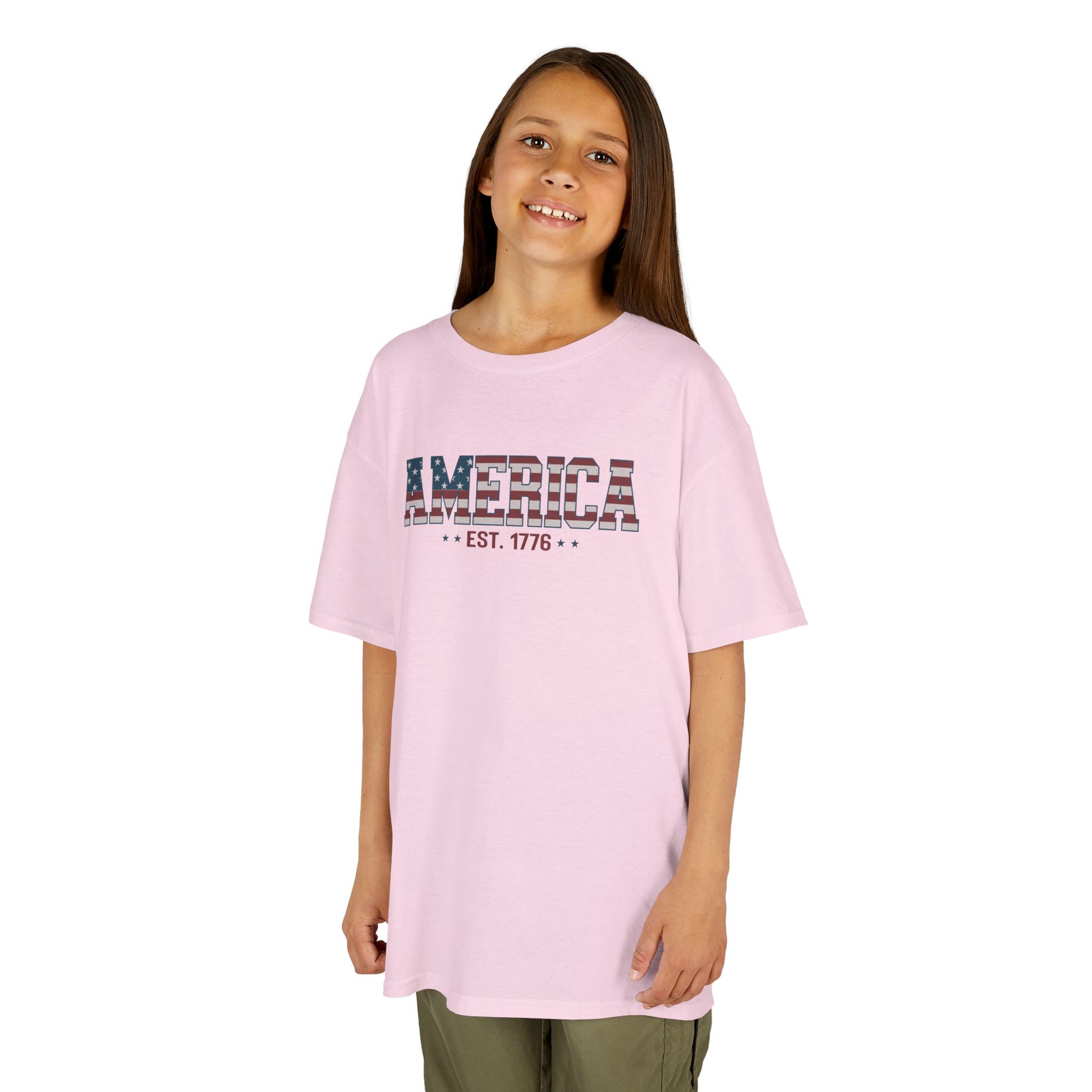 Young girl wearing a pink t-shirt with 'AMERICA EST. 1776' text on a white background