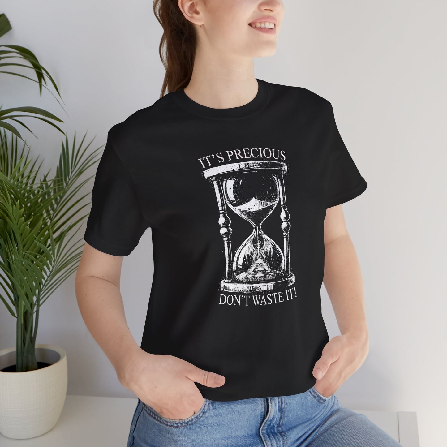Person wearing a black t-shirt with an hourglass design and text, standing indoors.