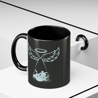 Black mug with a white angel and drum set design on a white background