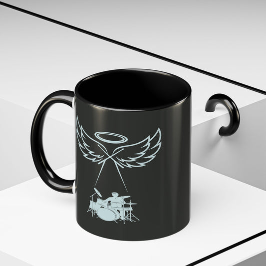 Black mug with a white angel and drum set design on a white background
