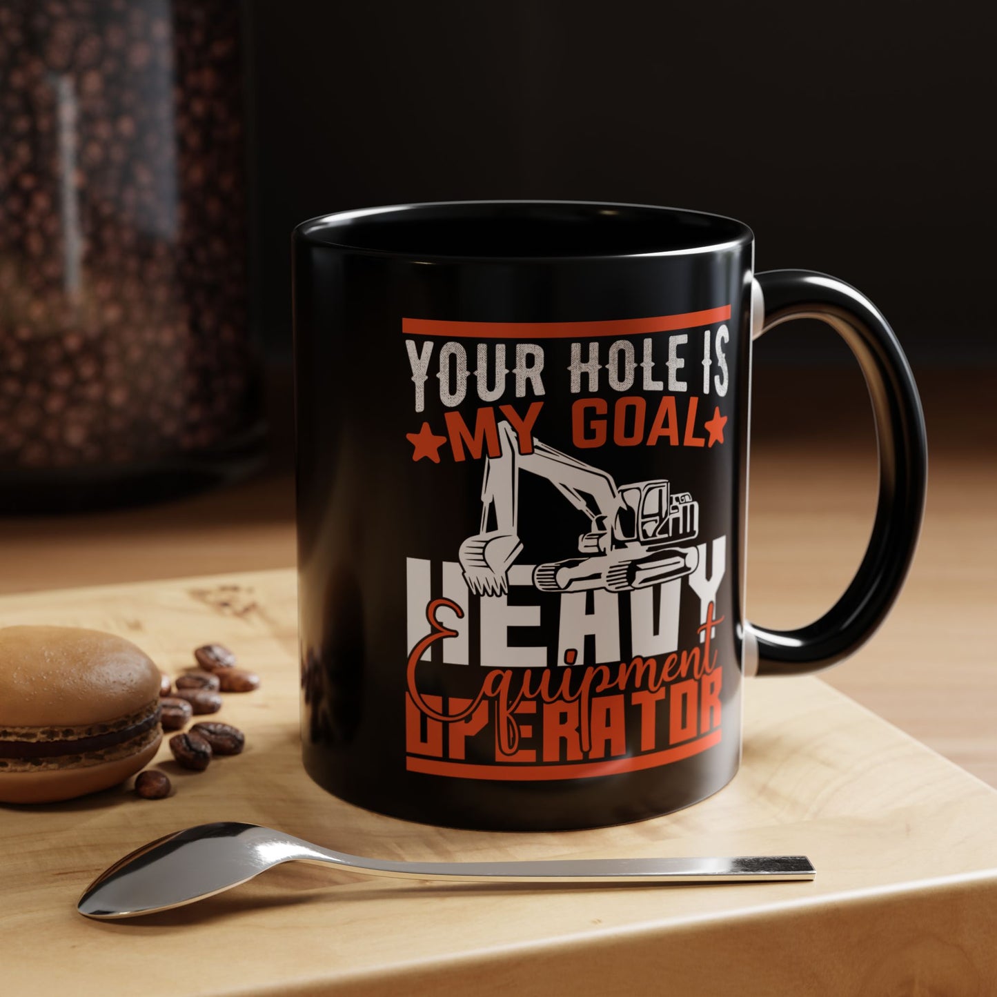 Black mug with humorous design on a wooden surface with coffee beans and a macaron.