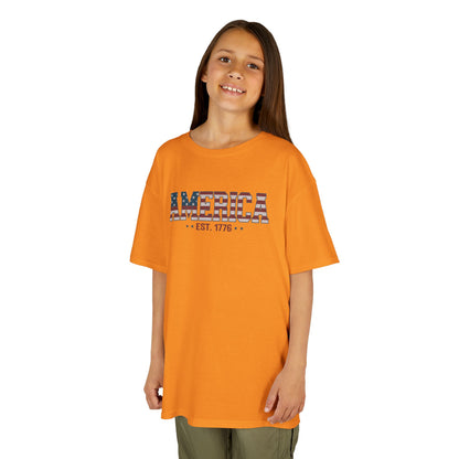 Child wearing an orange t-shirt with 'AMERICA EST. 1776' text on a white background
