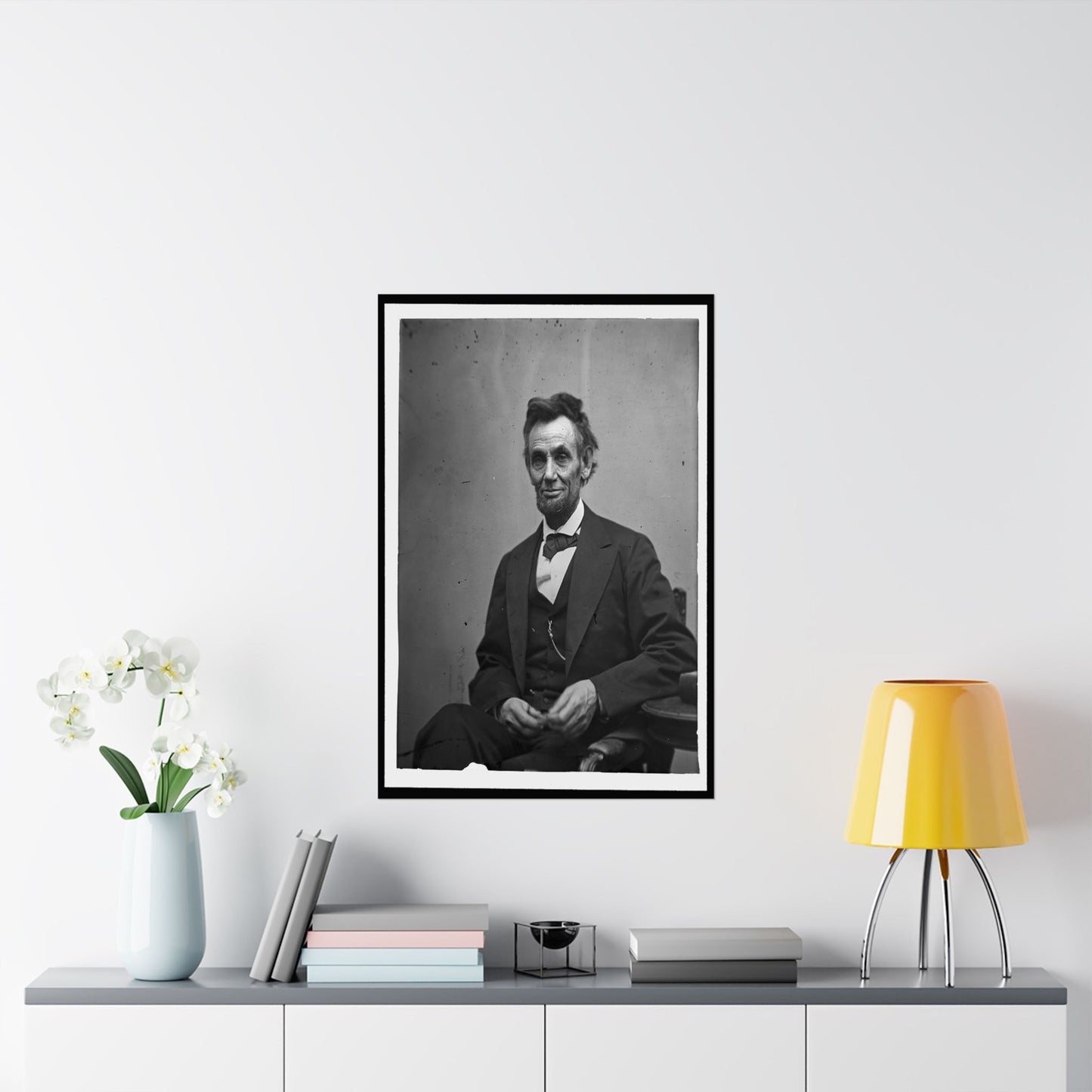 Framed portrait of a historical figure on a wall above a table with decor items.