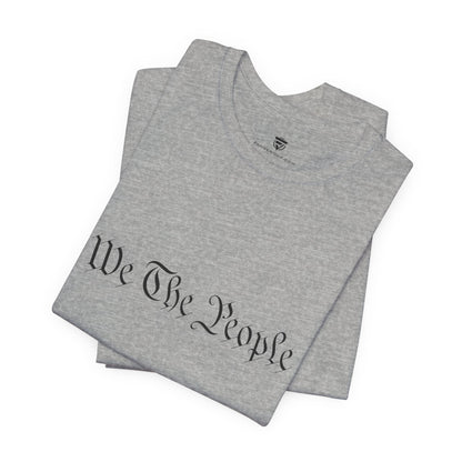Gray t-shirt with 'We The People' printed on it, folded and displayed against a white background