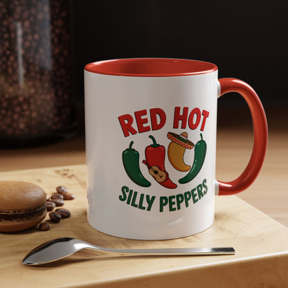 White mug with red interior and handle, featuring 'Red Hot Silly Peppers' design, on a wooden surface with coffee beans and a spoon.