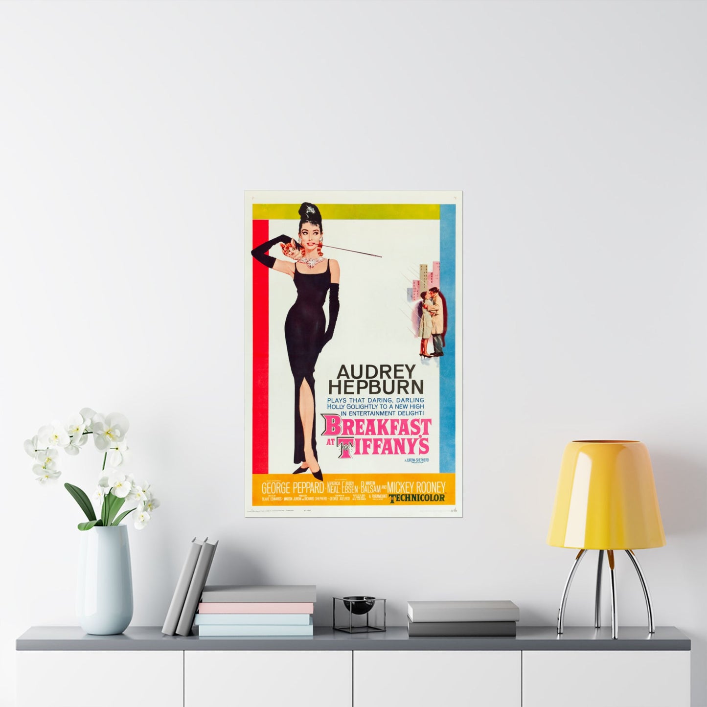 Framed movie poster of Audrey Hepburn from 'Breakfast at Tiffany's' on a wall above a shelf with decor items.