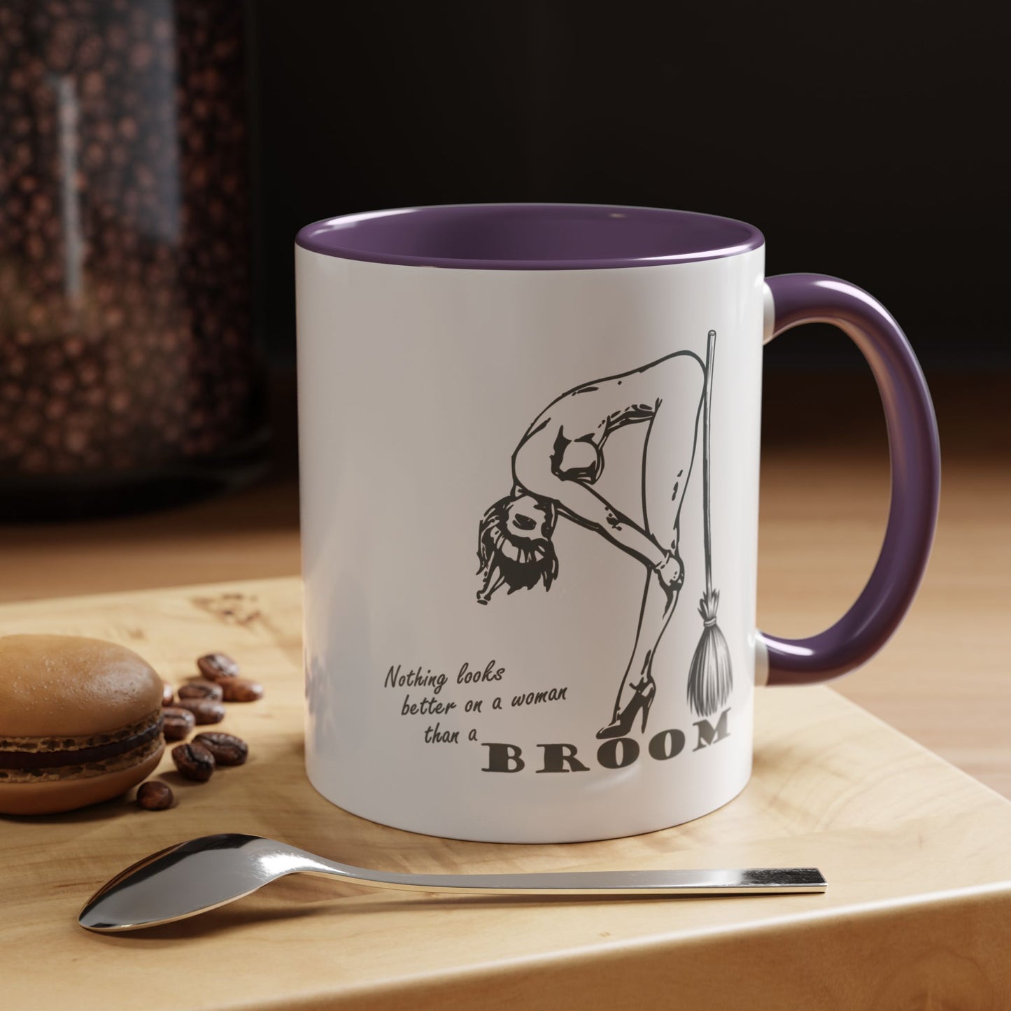 Mug with a humorous design and text on a wooden surface with coffee beans and a spoon.
