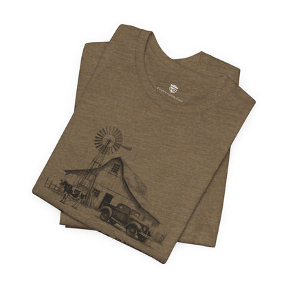 Folded brown t-shirt with a graphic design of a barn and windmill 