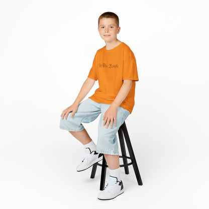Young boy sitting on a stool wearing an orange t-shirt, light blue jeans, and white sneakers on a white background