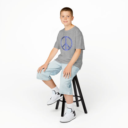 Young boy sitting on a stool wearing a gray t-shirt, light blue jeans, and white sneakers on a white background